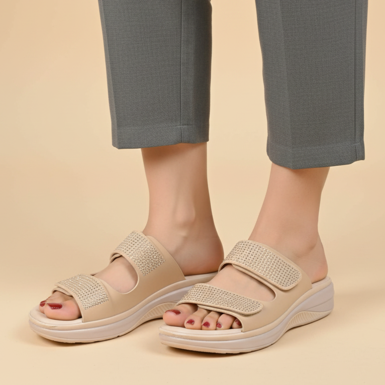 Beige sandals worn with gray pants on a beige background