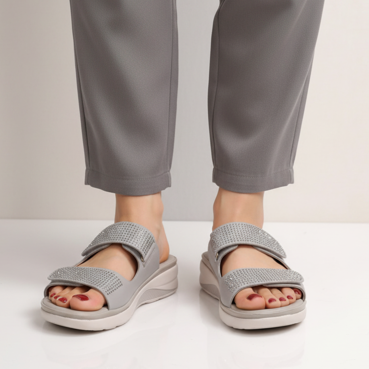 Person wearing gray sandals and pants on a plain background