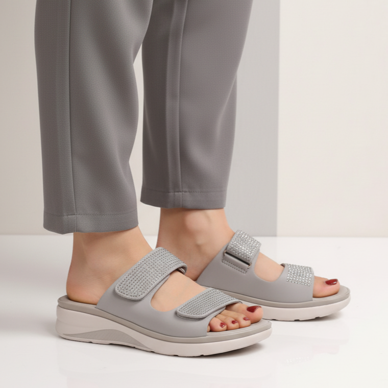 Gray sandals worn with gray pants on a neutral background