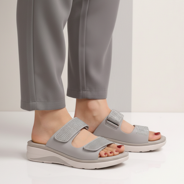 Gray sandals worn with gray pants on a neutral background