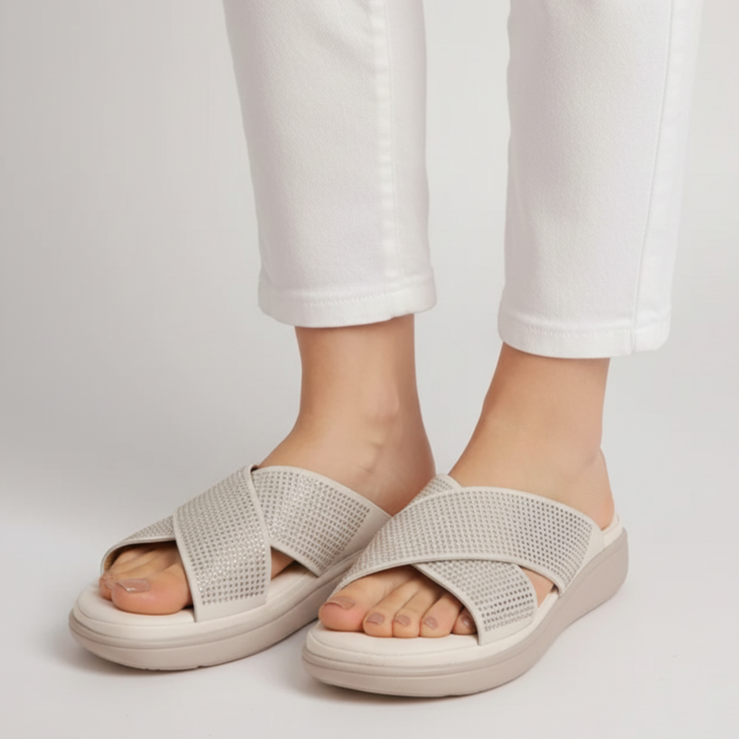 Light gray sandals worn with white pants on a light gray background