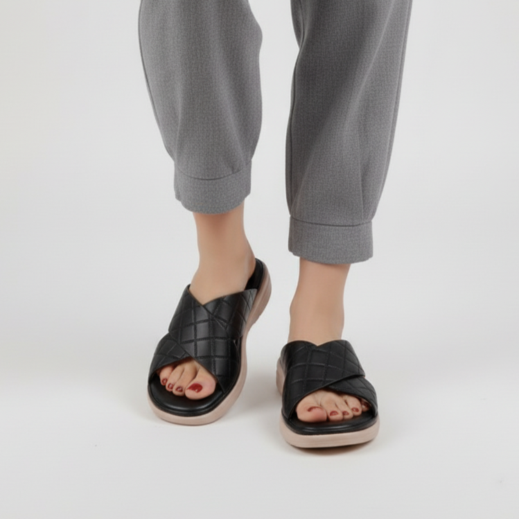 Person wearing black sandals and gray pants on a white background