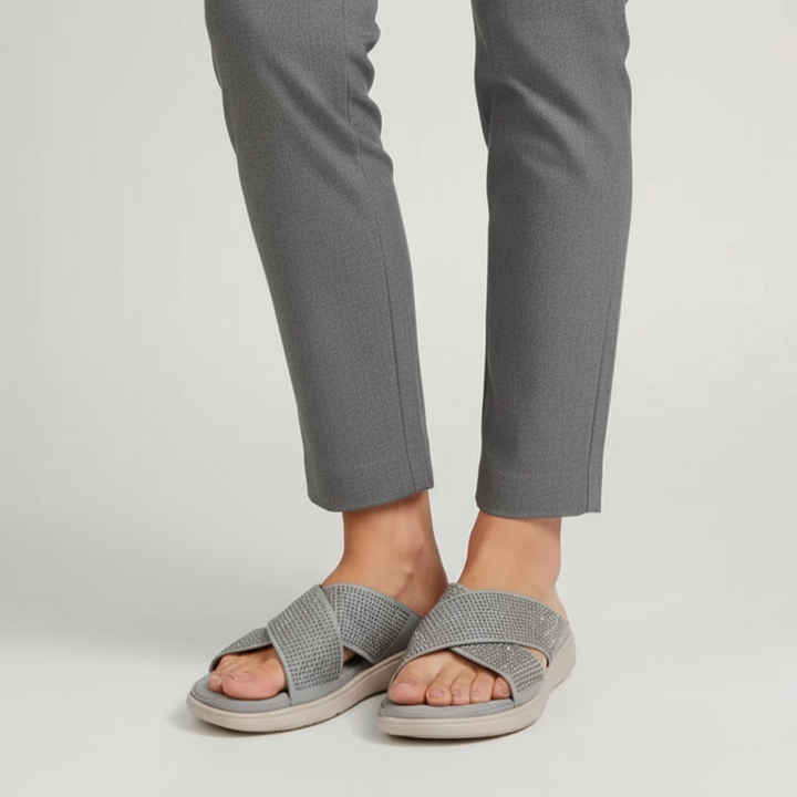Person wearing gray sandals and gray pants on a white background