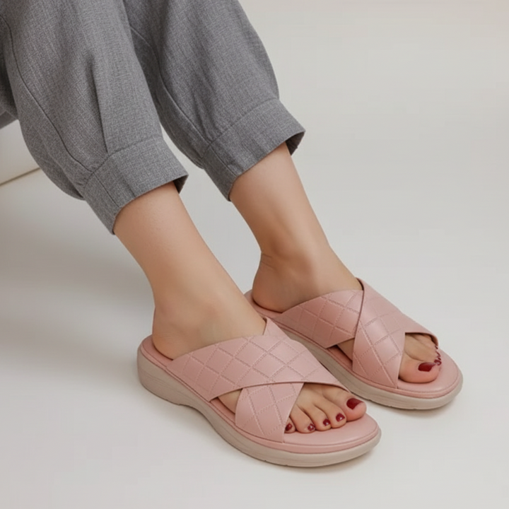 Pink sandals worn with gray pants on a light background