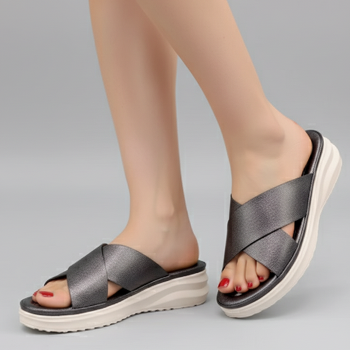 Gray sandals worn on feet against a gray background