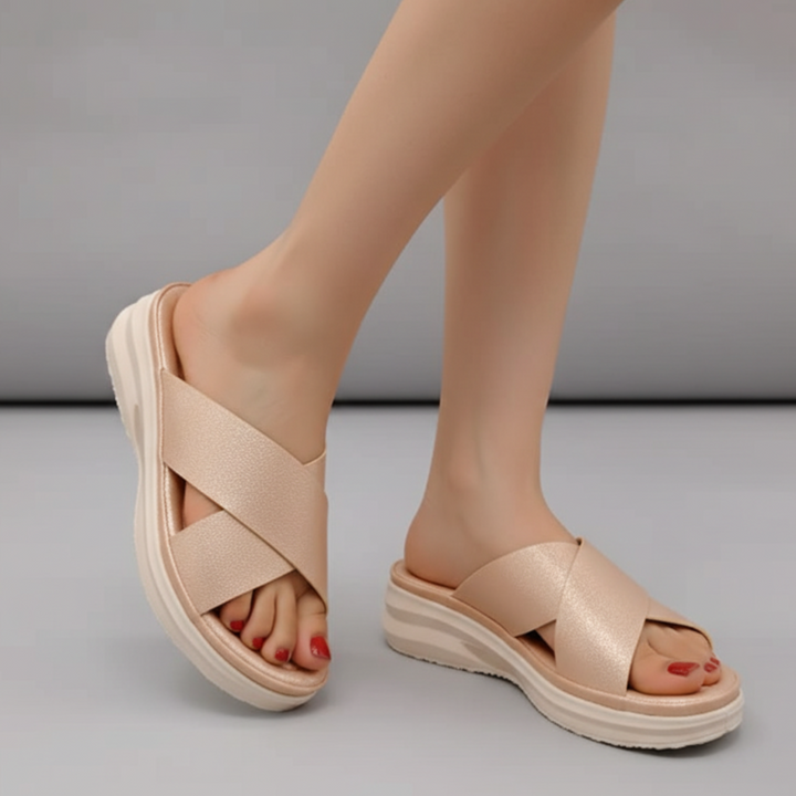 Beige sandals worn by a person on a gray background