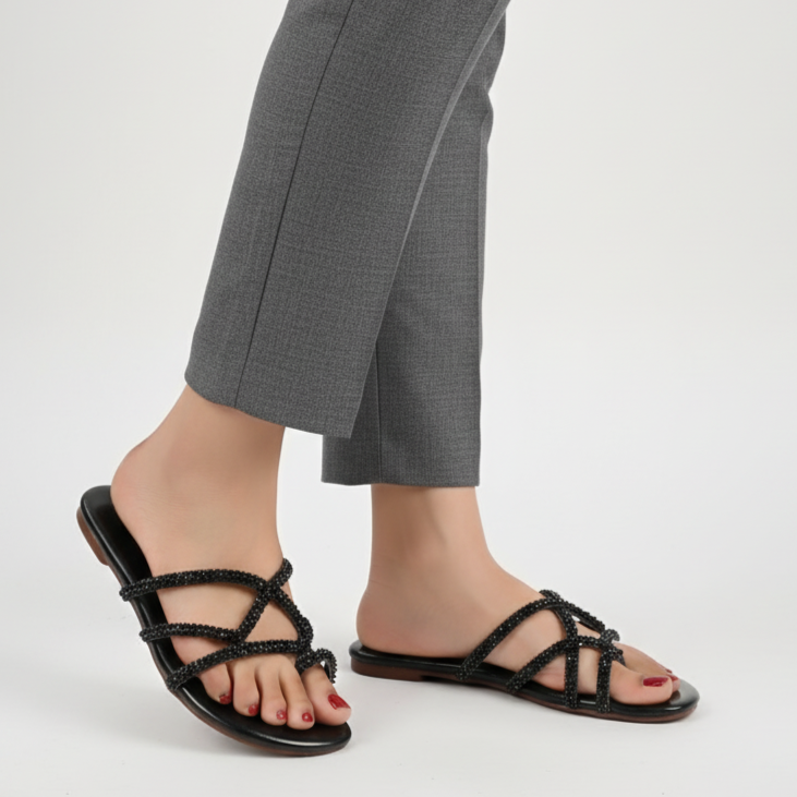 Person wearing black strappy sandals with gray pants on a white background