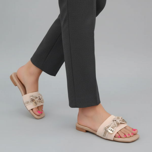 Beige sandals worn with black pants on a gray background