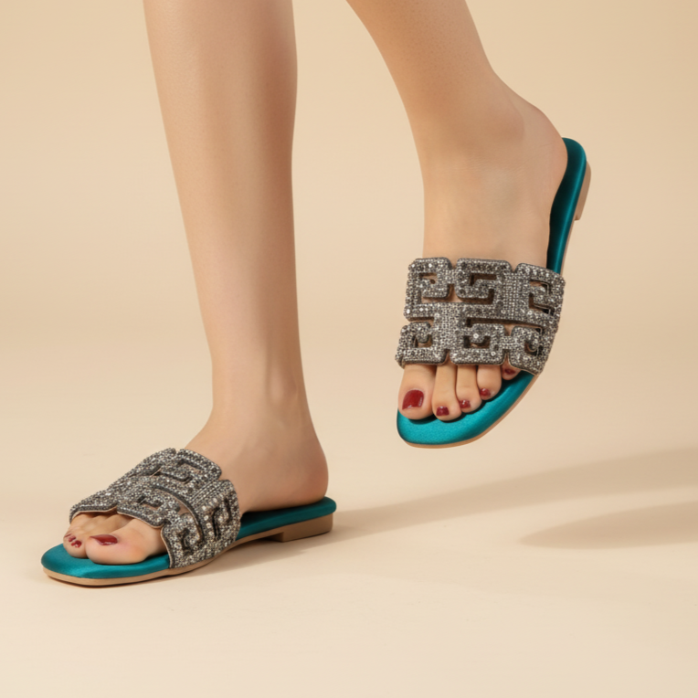 Teal sandals with decorative straps worn by a person on a beige background