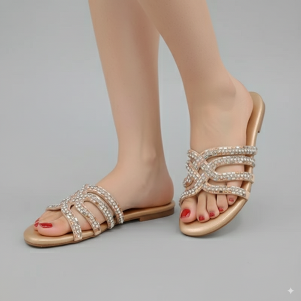 Gold sandals with pearl embellishments worn by a person on a gray background
