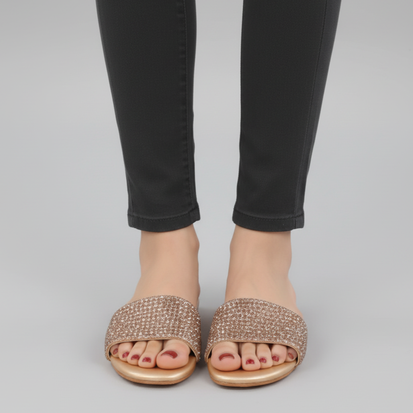 Person wearing sparkly sandals and black pants on a gray background