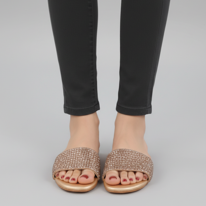 Person wearing sparkly sandals and black pants on a gray background