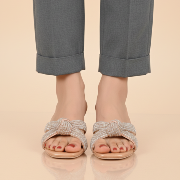 Person wearing gray pants and sandals on a beige background
