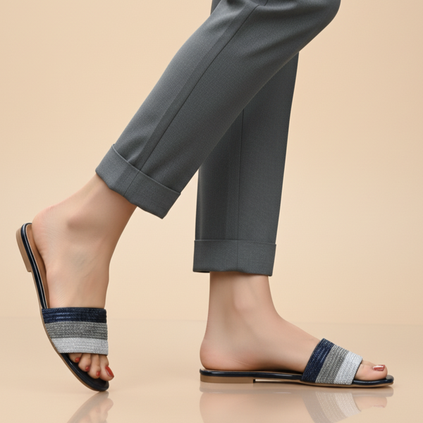 Person wearing navy sandals with a striped strap on a beige background