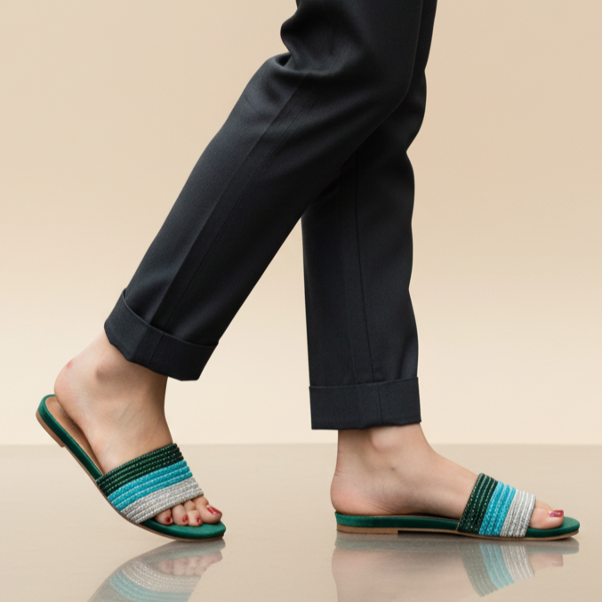 Person wearing black pants and green sandals on a beige background
