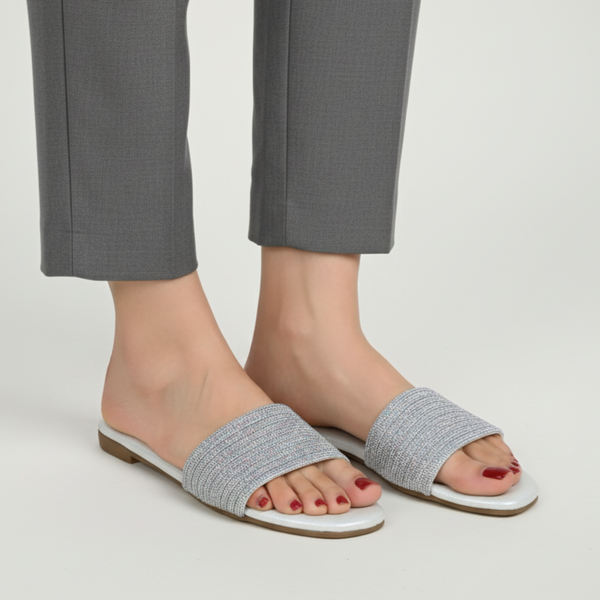Gray sandals worn with gray pants on a plain background