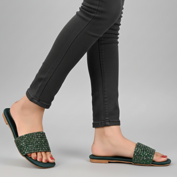 Person wearing green sandals with black pants on a gray background