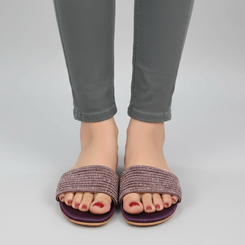 Purple sandals worn with gray pants on a light gray background