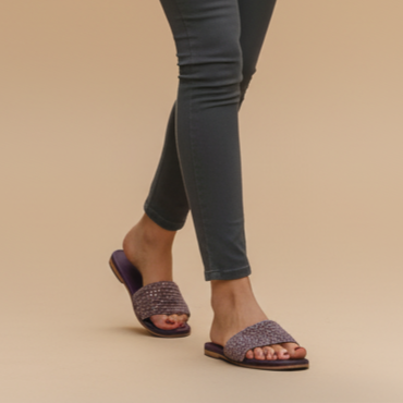 Woman wearing a white t-shirt and gray pants against a beige background