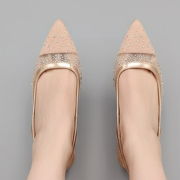 Beige pointed-toe shoes with rhinestone details on a gray background