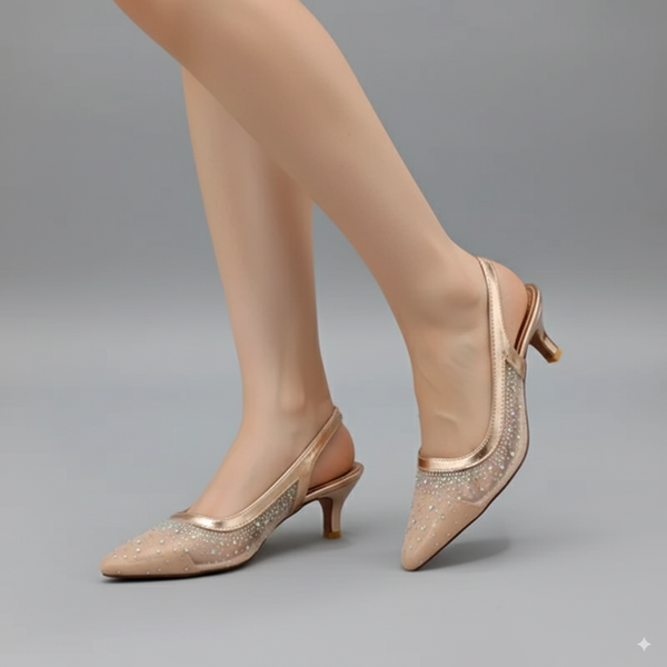 Beige high-heeled shoes with glittery details worn by a person on a gray background