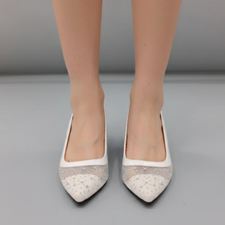 White pointed-toe shoes with embellishments on a gray background