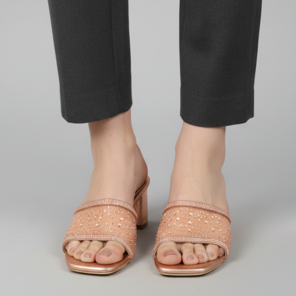 Person wearing black pants and pink sandals on a gray background