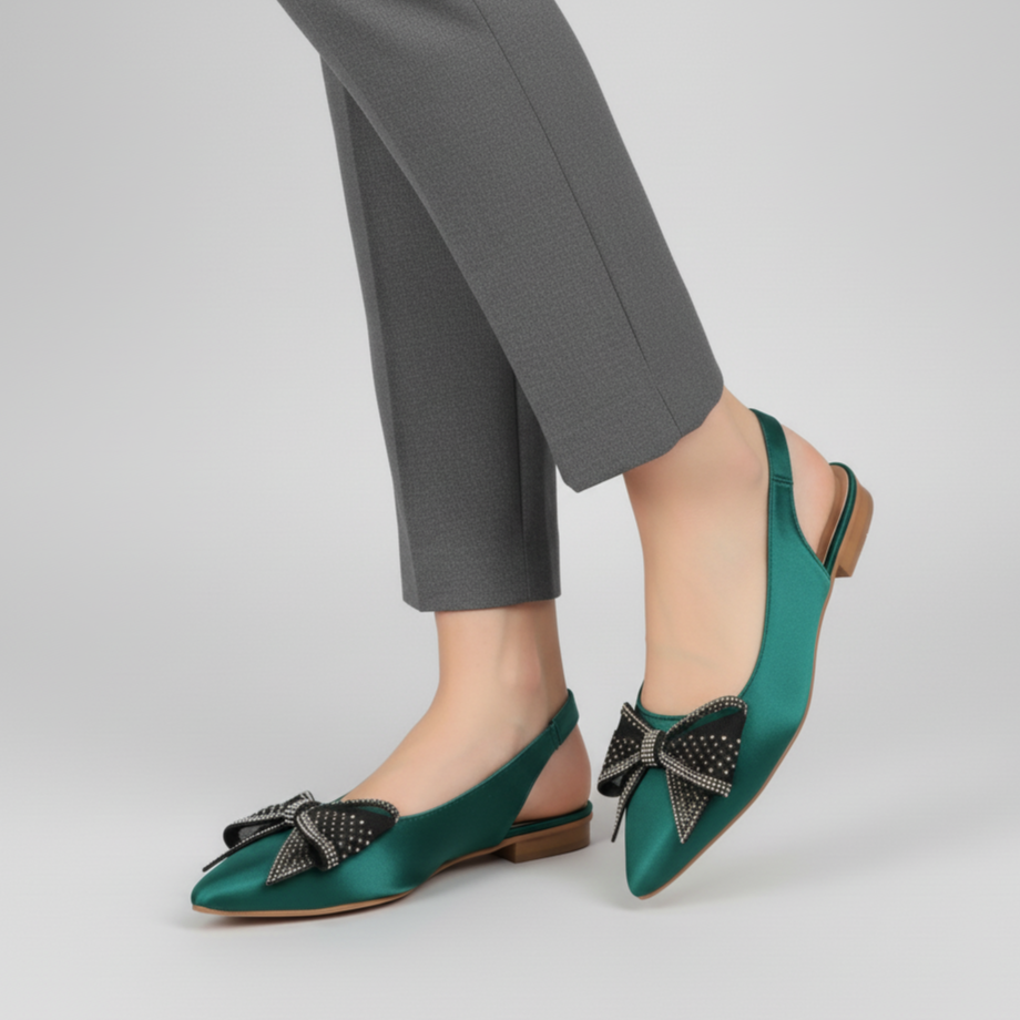 Green shoes with bow details worn with gray pants on a light gray background