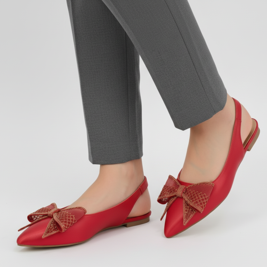 Red flats with bow details worn with gray pants on a white background