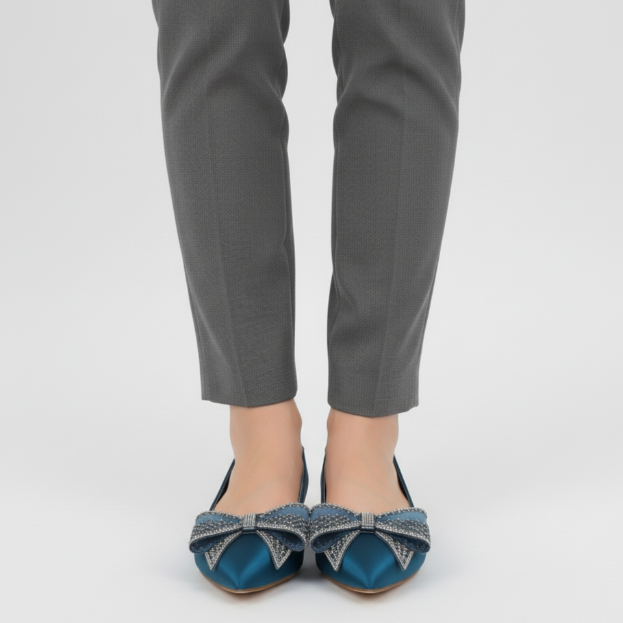 Person wearing gray pants and blue shoes with decorative bows on a light gray background