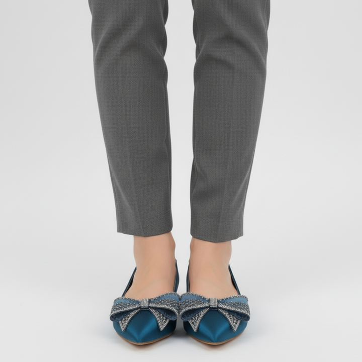 Person wearing gray pants and blue shoes with decorative bows on a light gray background