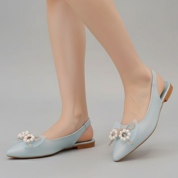 Light blue flat shoes with pearl embellishments on a gray background