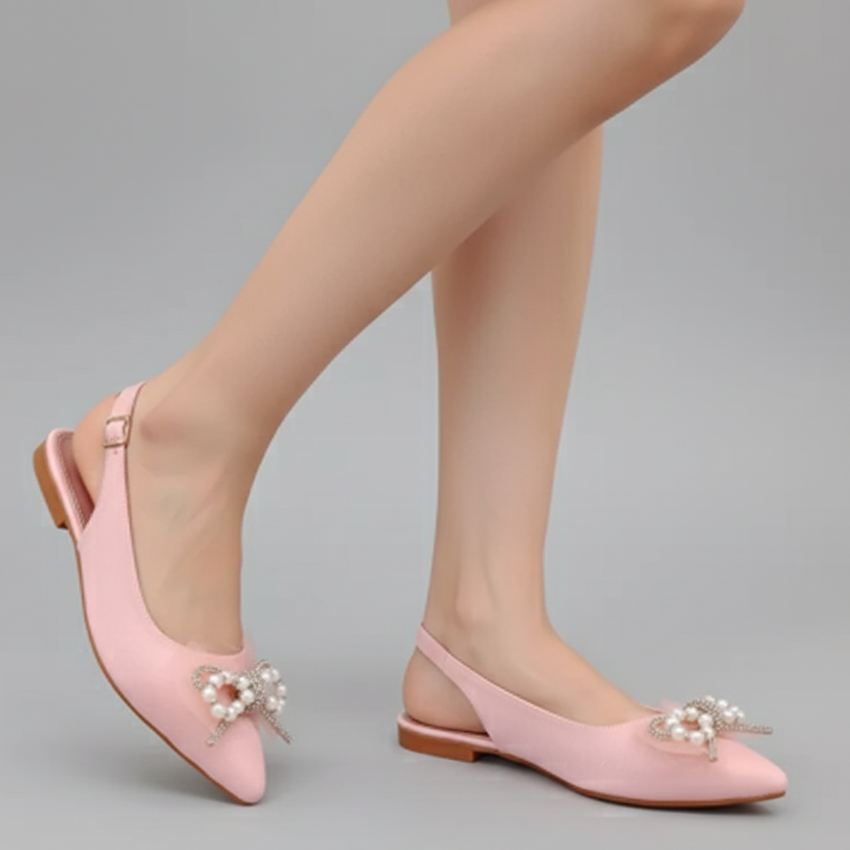 Pink shoes with pearl embellishments worn by a person on a gray background