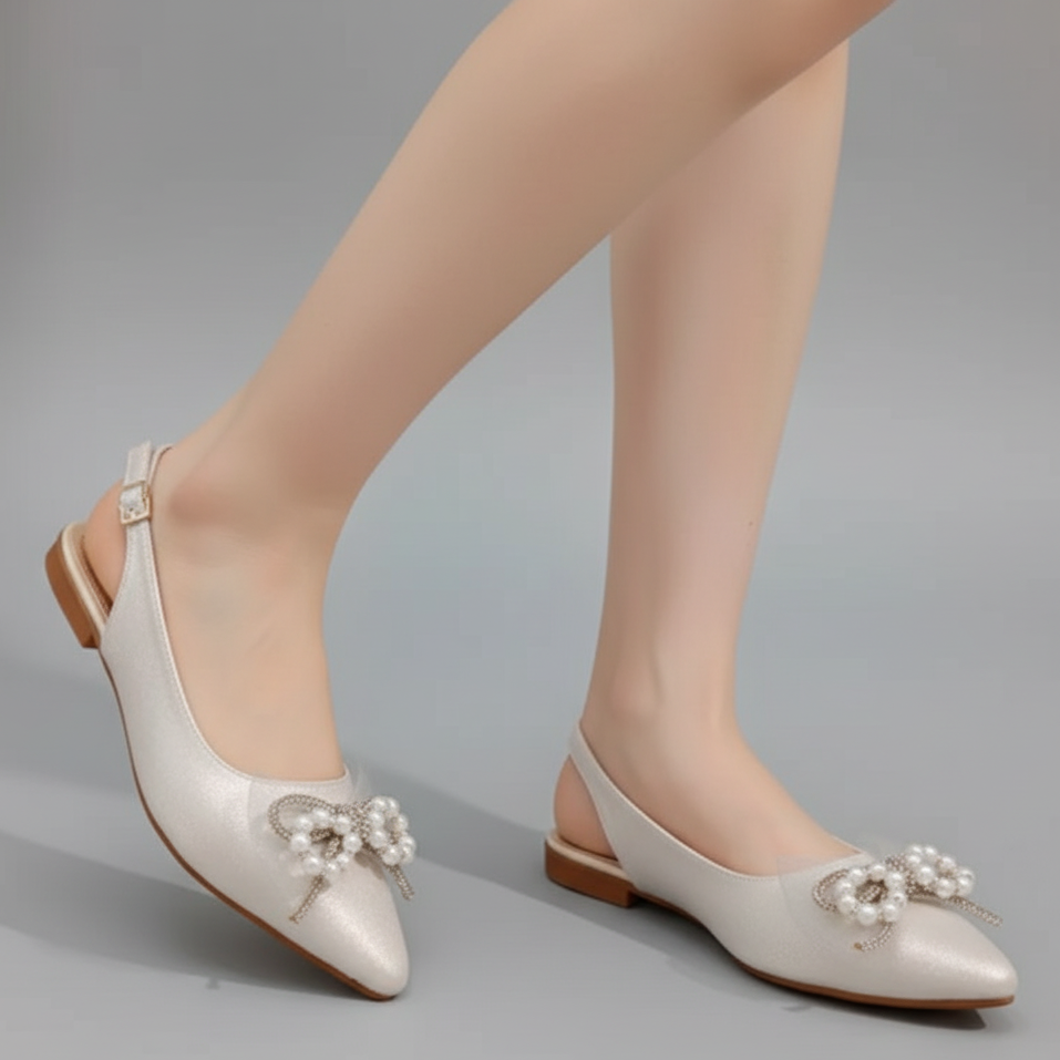 White pointed-toe shoes with floral embellishments on a gray background