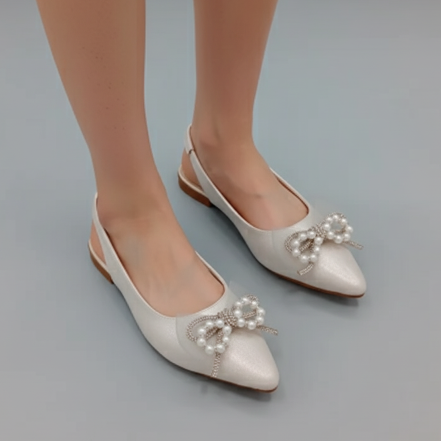White flat shoes with pearl embellishments on a gray background