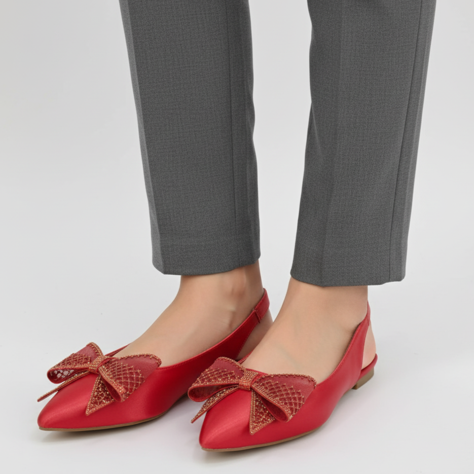 Red flats with bow details worn with gray pants on a white background
