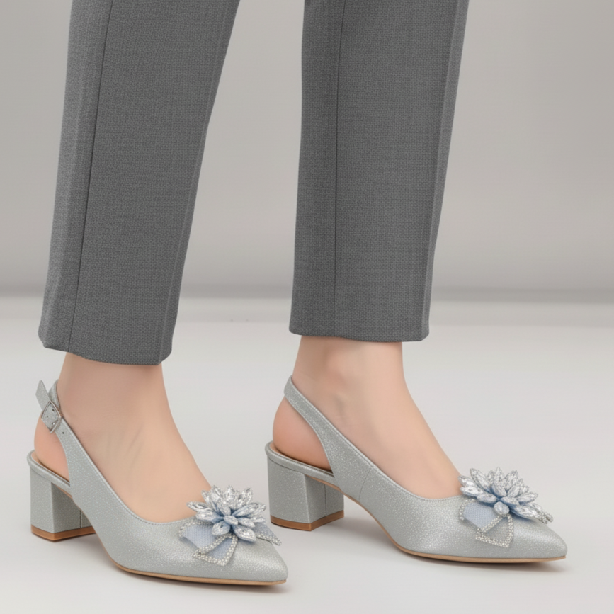 Light blue high-heeled shoes with floral embellishments worn with gray pants on a neutral background