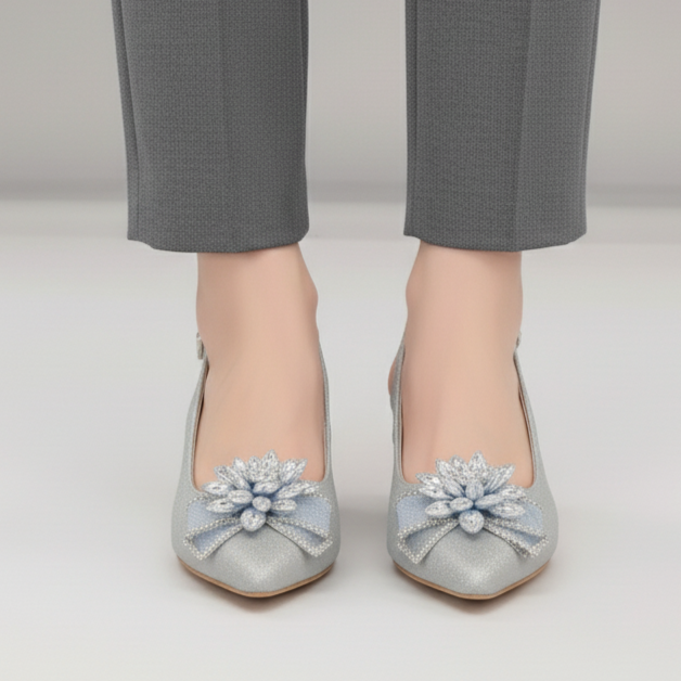 Gray shoes with floral embellishments worn with gray pants on a plain background