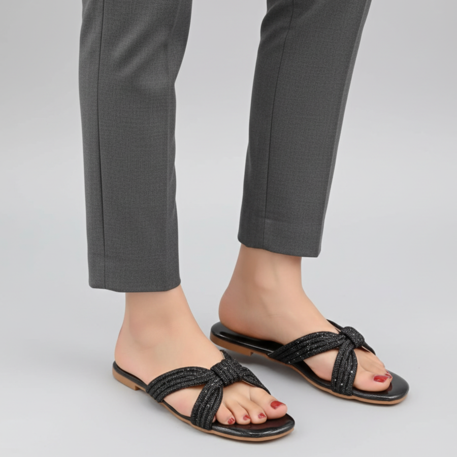 Black sandals worn with gray pants on a light gray background
