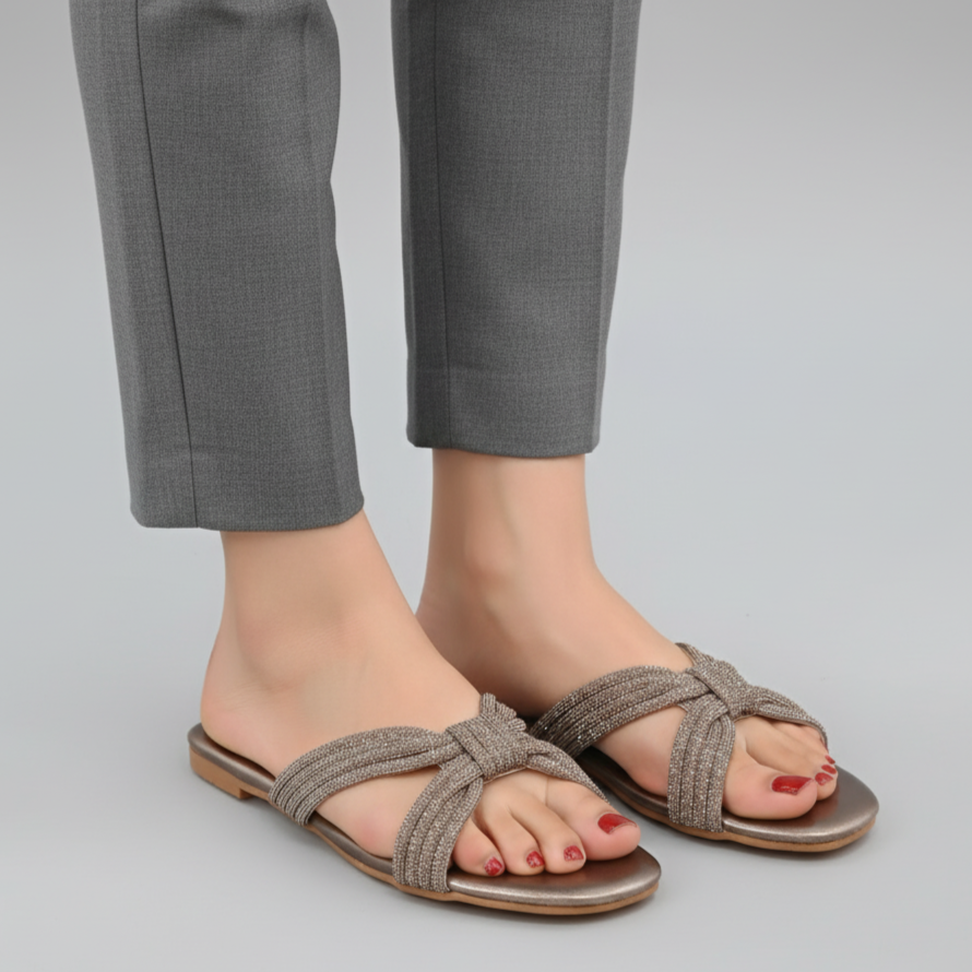 Pair of brown sandals worn with gray pants on a light gray background