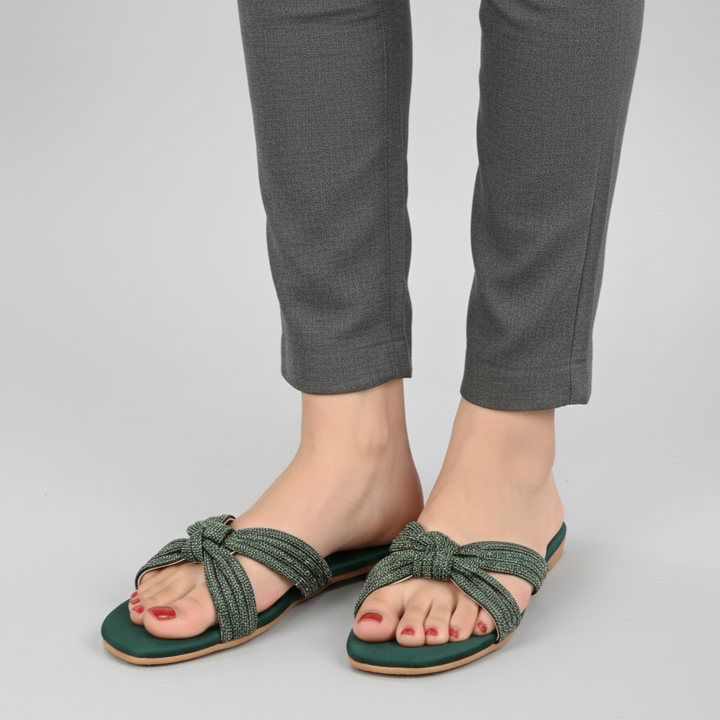 Green sandals worn with gray pants on a light gray background