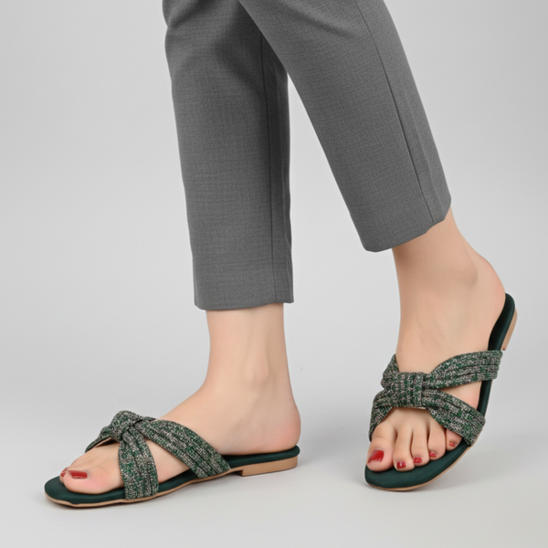 Green sandals worn with gray pants on a light gray background
