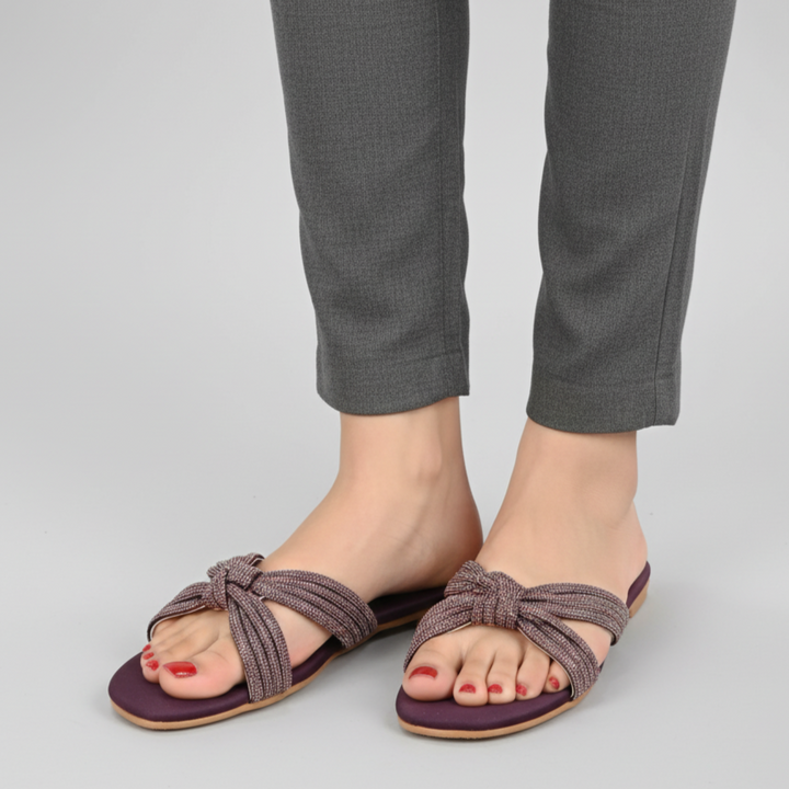 Purple sandals worn with gray pants on a light gray background