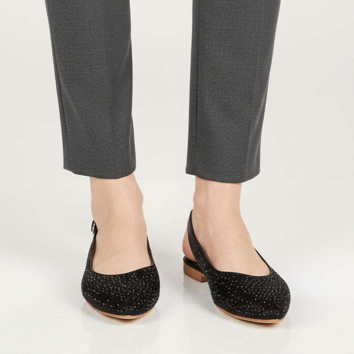 Black flat shoes worn with gray pants on a white background