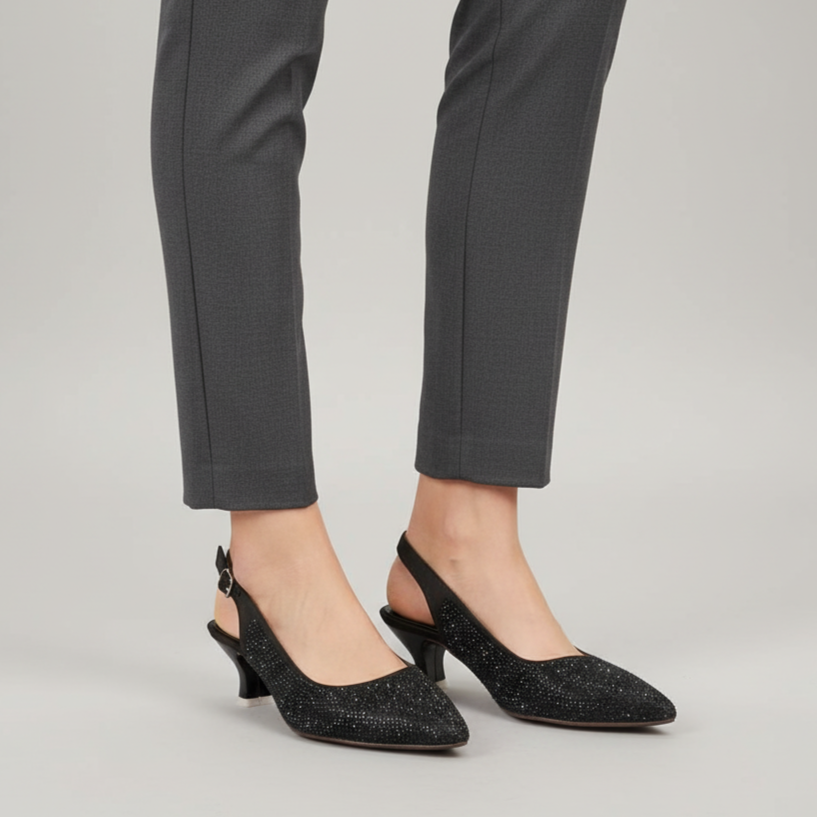 Person wearing gray pants and black glittery shoes on a light gray background