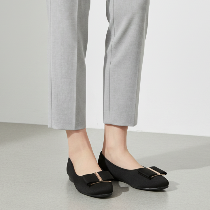 Person wearing black shoes with a buckle and gray pants on a light background