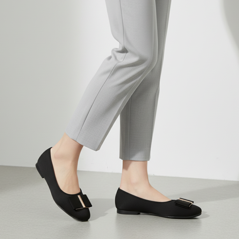 Person wearing black flat shoes and gray pants on a light background