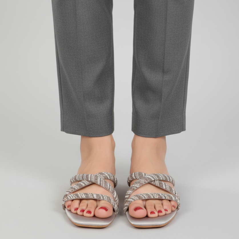Person wearing gray pants and striped sandals on a plain background