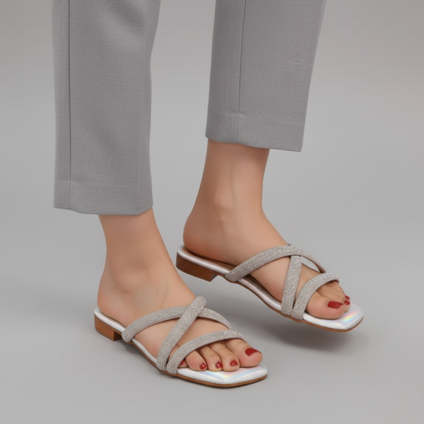 Gray sandals worn with gray pants on a neutral background