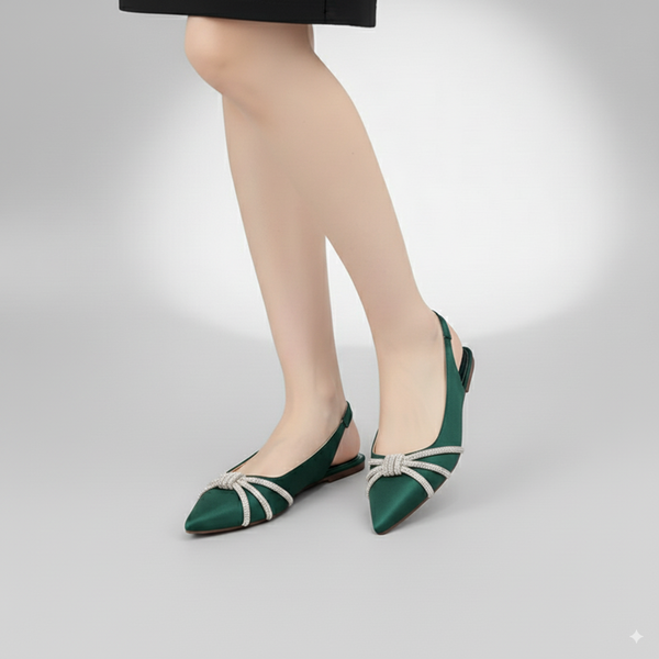 Green pointed-toe shoes with white straps worn by a person on a light gray background
